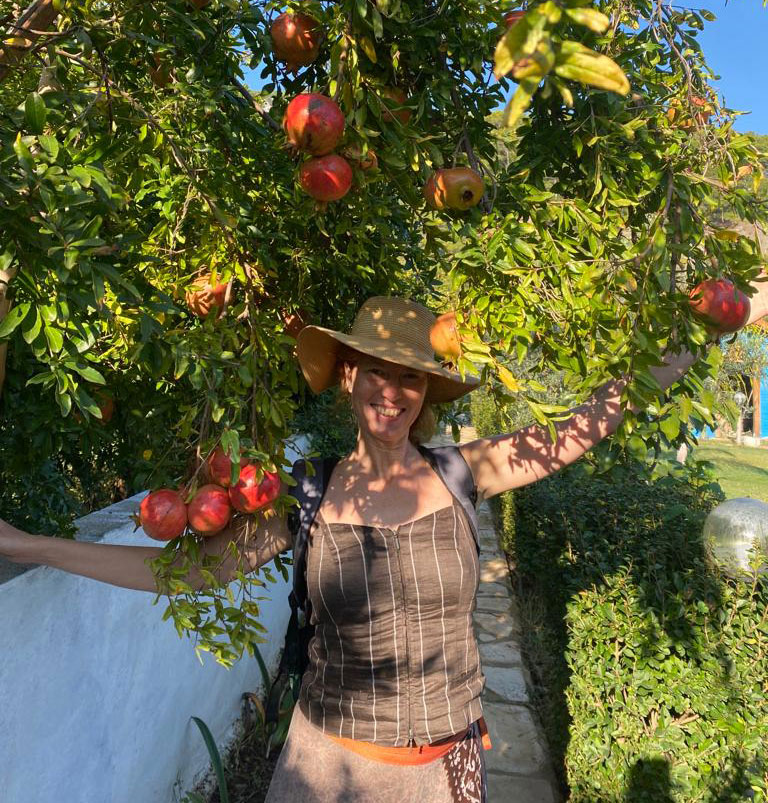 Lenka mit Hut lächelnd unter einem Apfelbaum